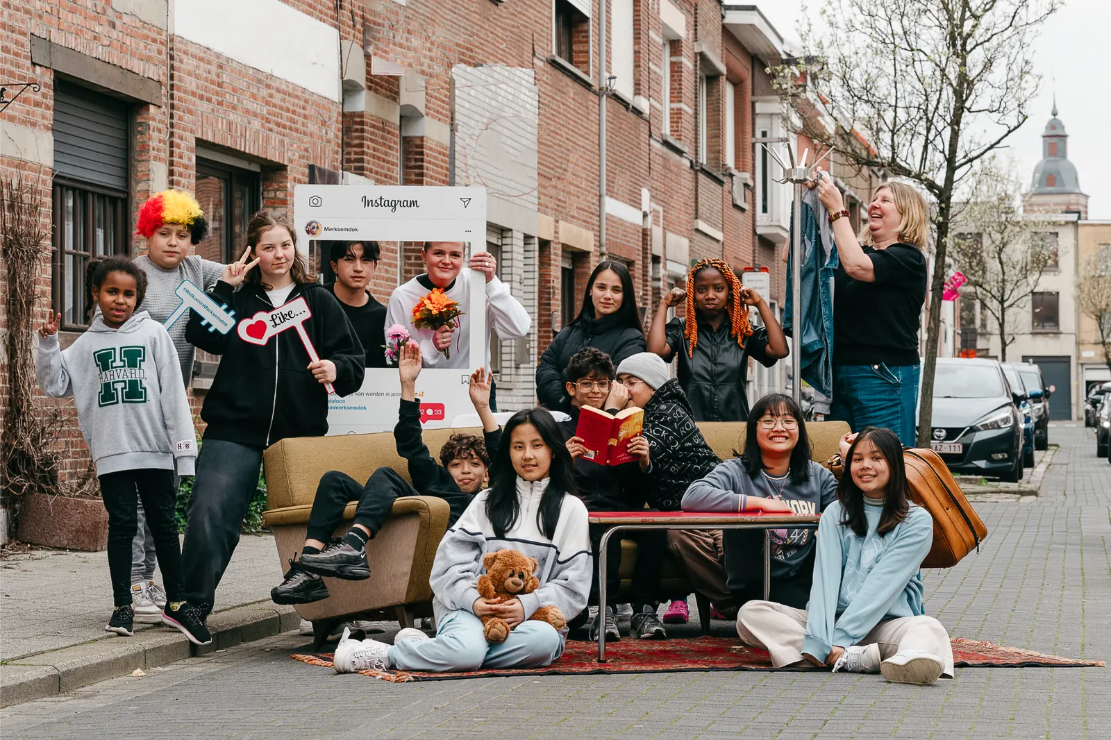 Jongeren van Buren poseren met een zetel, tapijt en Instagram-kader midden in een straat in Merksem